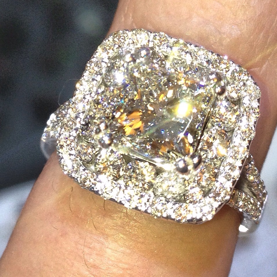 Halo style diamond engagement ring with a cushion cut diamond center stone.